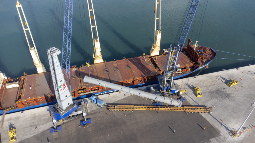 Vista aérea de una maniobra de carga de proyecto en Altamira Terminal Portuaria: dos grúas móviles izan una pieza de gran tamaño junto a un buque